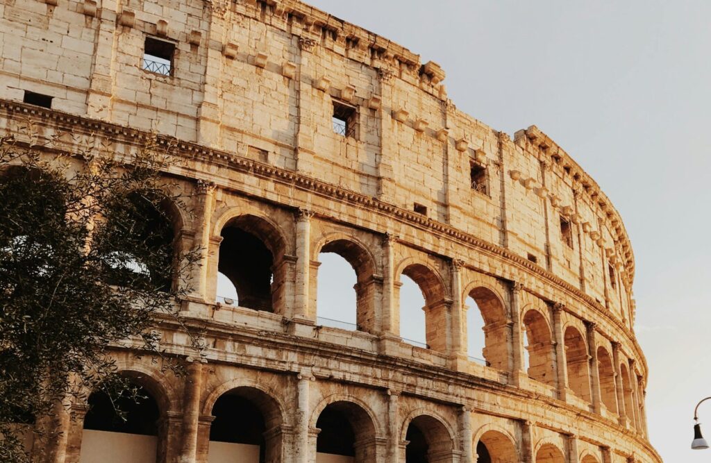 Iconic view of the Colosseum in Rome, Italy, at sunset with tourists outside.