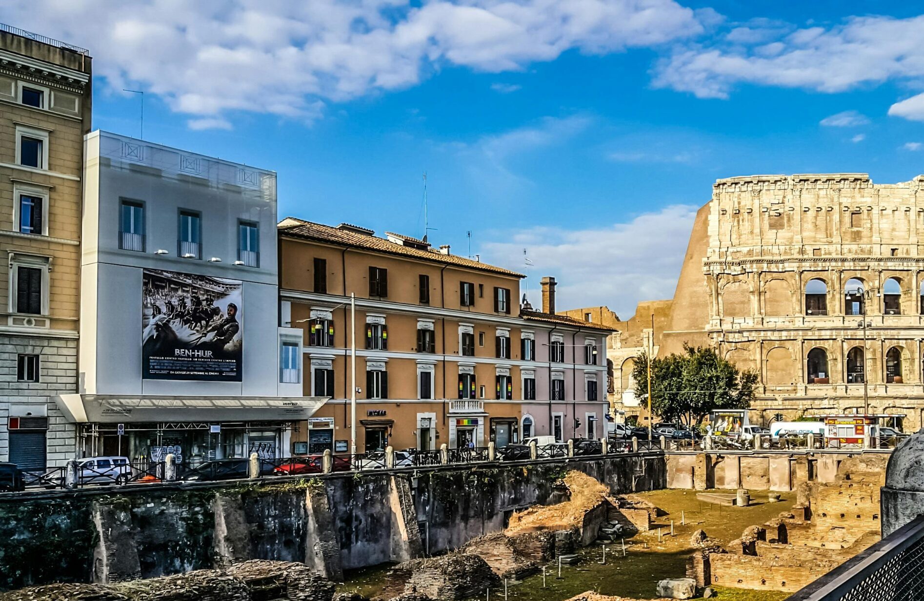 Daylight view of the historic Colosseum in Rome with vibrant city buildings.